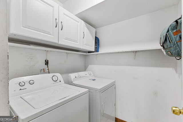 clothes washing area featuring washing machine and dryer and cabinets