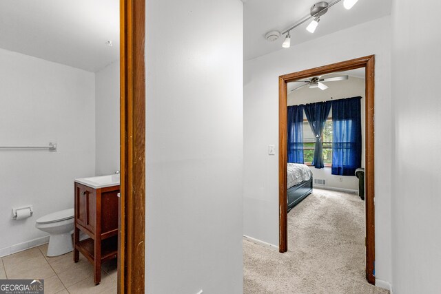 bathroom with tile patterned floors, rail lighting, toilet, and ceiling fan