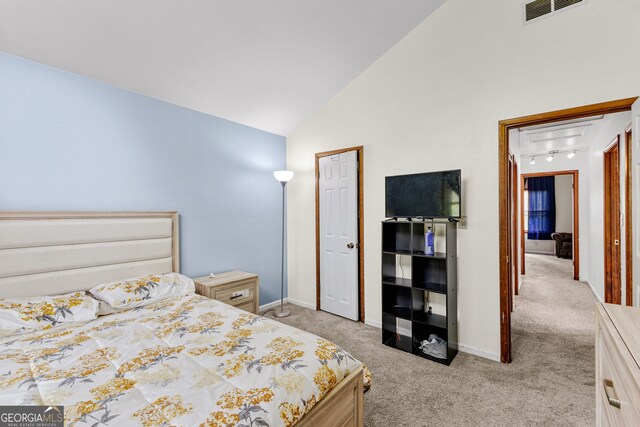 carpeted bedroom with high vaulted ceiling