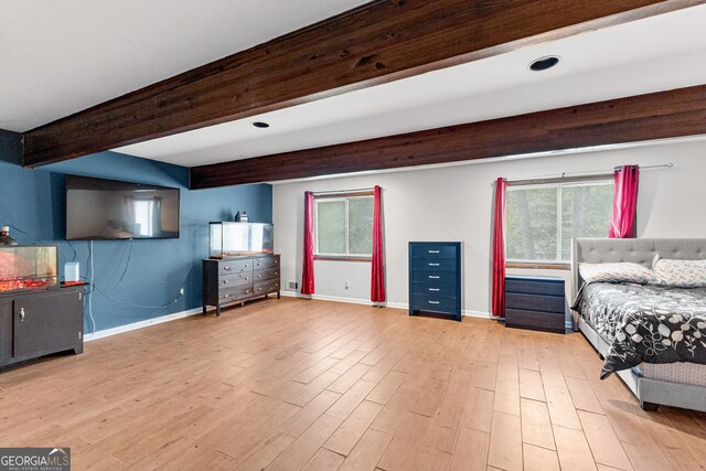 bedroom with multiple windows, beam ceiling, and light wood-type flooring