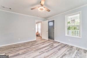 spare room featuring ornamental molding, ceiling fan, and light wood-type flooring