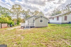 rear view of property with a wooden deck and a lawn