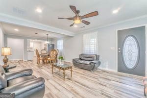 living room with ornamental molding, ceiling fan, and light hardwood / wood-style flooring