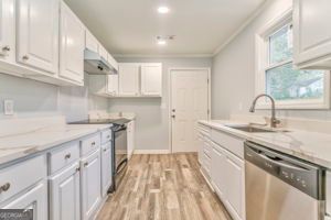 kitchen with light stone counters, white cabinets, sink, and dishwasher