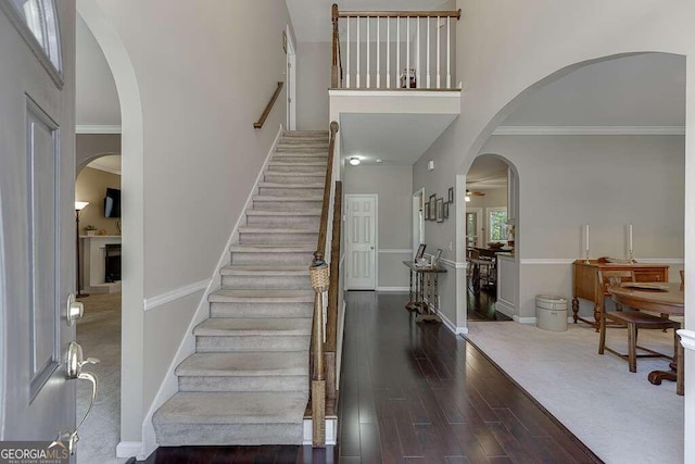 foyer with crown molding, dark wood-type flooring, and a high ceiling