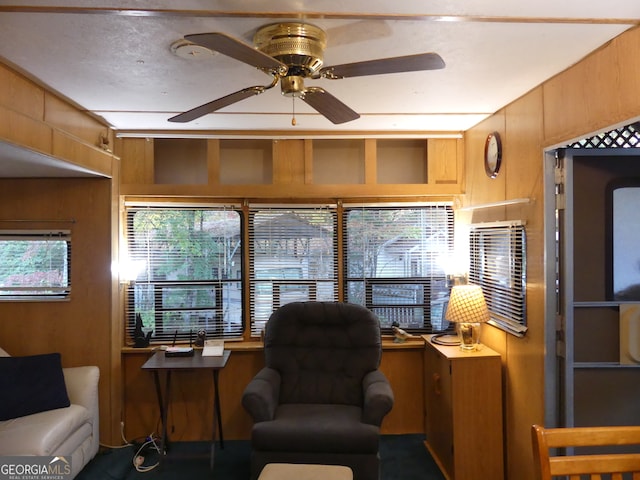 home office featuring a healthy amount of sunlight, ceiling fan, and wood walls