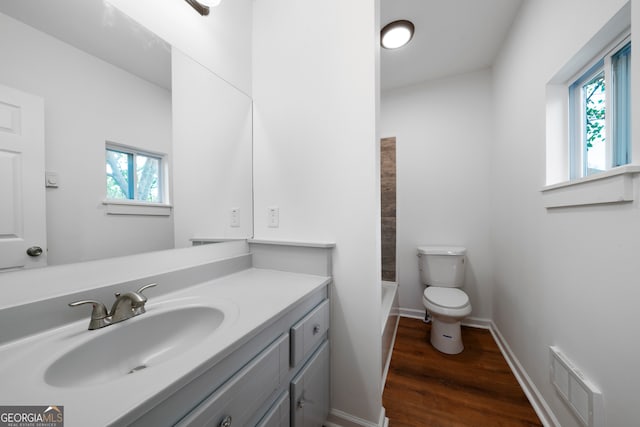 full bathroom featuring hardwood / wood-style floors, washtub / shower combination, vanity, and toilet