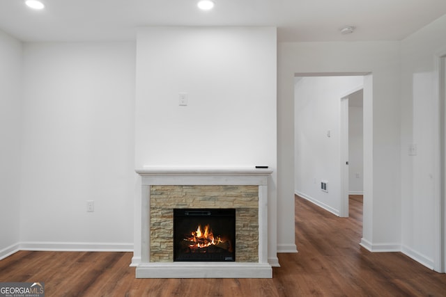 unfurnished living room featuring dark wood-type flooring and a stone fireplace