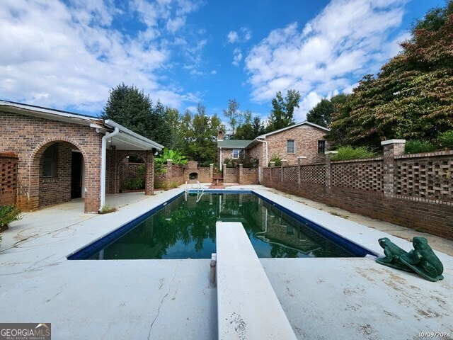 view of pool with a patio and a diving board