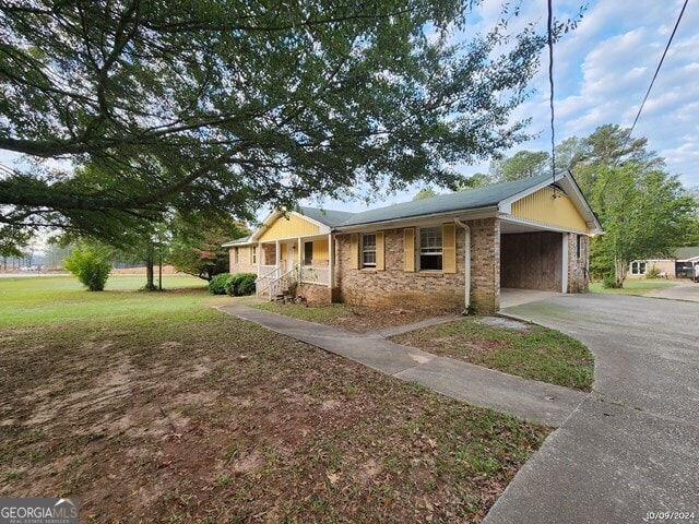 single story home with a carport, a front lawn, and a porch