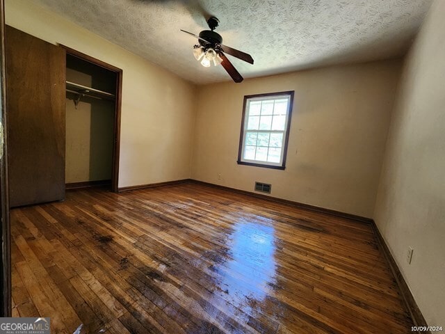 unfurnished bedroom featuring dark wood-type flooring, a textured ceiling, and ceiling fan