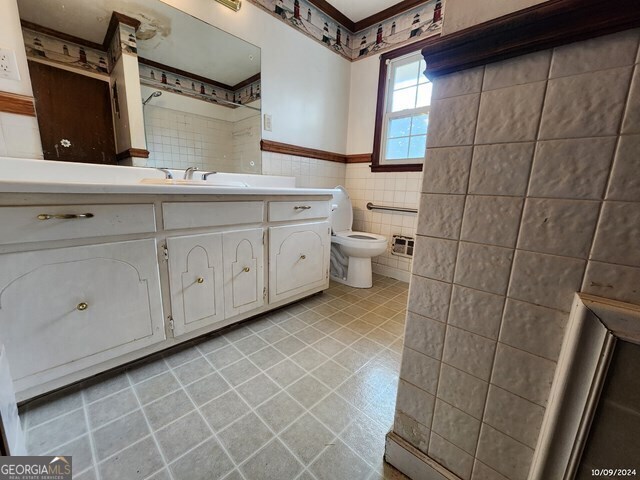 bathroom with tile walls, vanity, and toilet