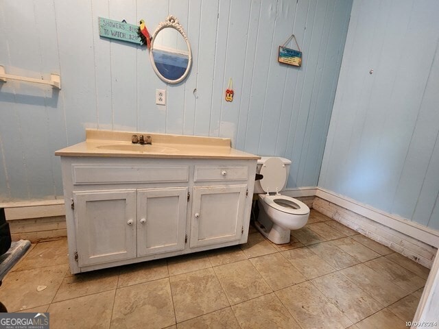 bathroom with vanity, toilet, and wood walls