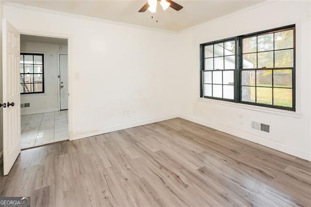 spare room with ornamental molding, ceiling fan, light wood-type flooring, and a wealth of natural light