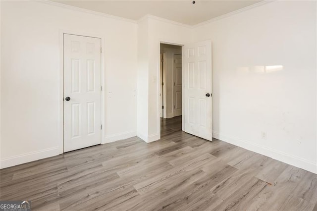 unfurnished bedroom featuring light hardwood / wood-style floors, crown molding, and a closet