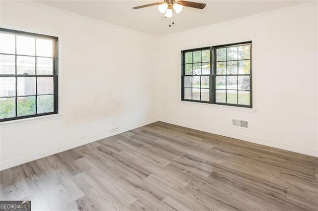 empty room featuring light hardwood / wood-style flooring, crown molding, and a wealth of natural light