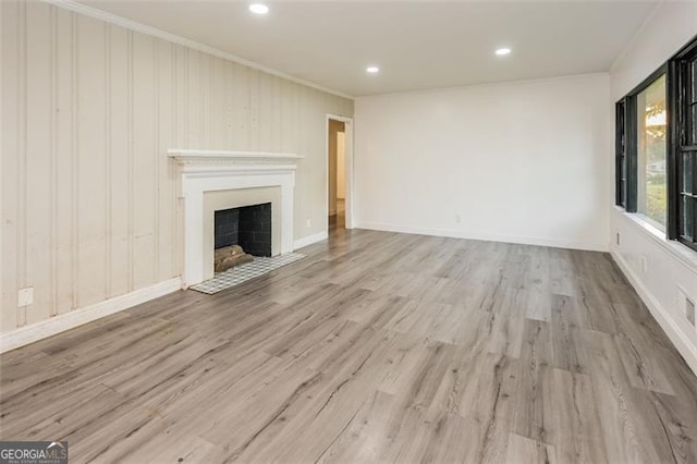 unfurnished living room with light hardwood / wood-style floors, wood walls, and ornamental molding