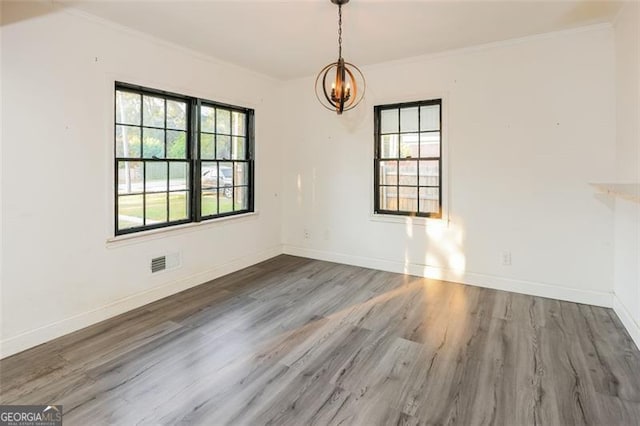 unfurnished dining area featuring dark wood-type flooring, crown molding, a wealth of natural light, and a chandelier