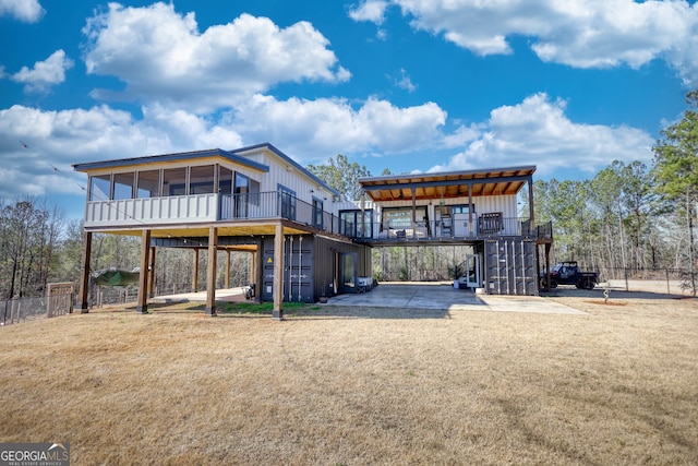 rear view of house featuring a patio area, a wooden deck, and a lawn