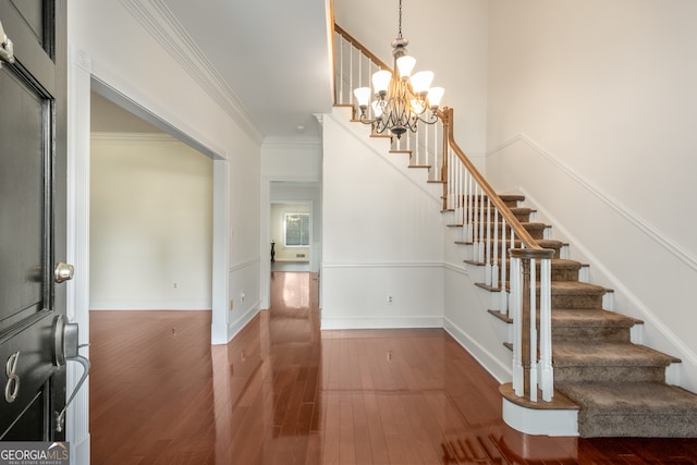 entrance foyer with an inviting chandelier, dark hardwood / wood-style floors, and crown molding