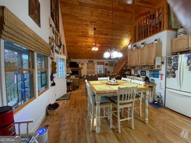 dining space with an inviting chandelier, high vaulted ceiling, light hardwood / wood-style floors, and wooden ceiling