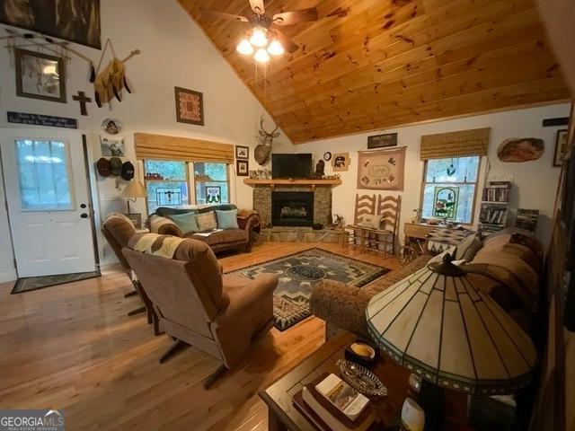 living room with hardwood / wood-style flooring, wooden ceiling, a fireplace, high vaulted ceiling, and ceiling fan