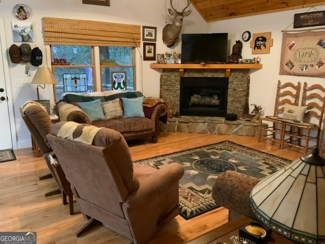 living room with vaulted ceiling, a fireplace, light hardwood / wood-style floors, and wooden ceiling