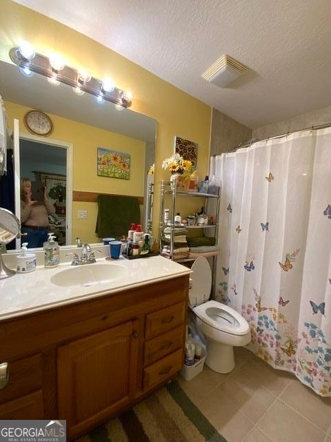 bathroom featuring vanity, a textured ceiling, toilet, and tile patterned floors