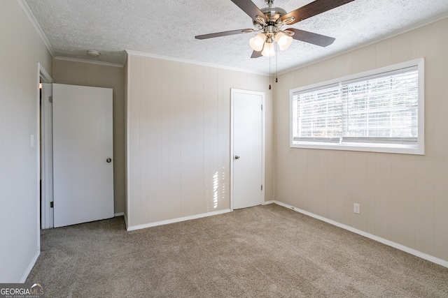 unfurnished bedroom with carpet, ceiling fan, a textured ceiling, a closet, and crown molding