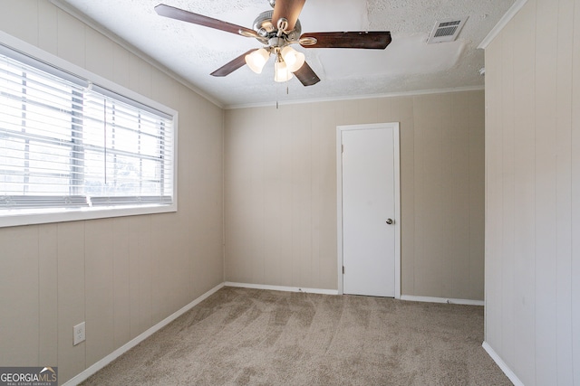 empty room with light carpet, crown molding, a textured ceiling, and ceiling fan