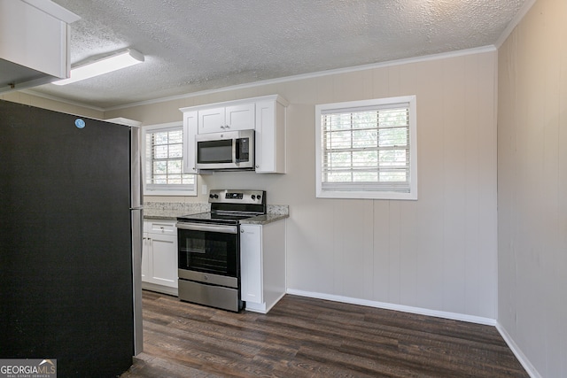 kitchen with a wealth of natural light, dark wood-type flooring, appliances with stainless steel finishes, and white cabinets