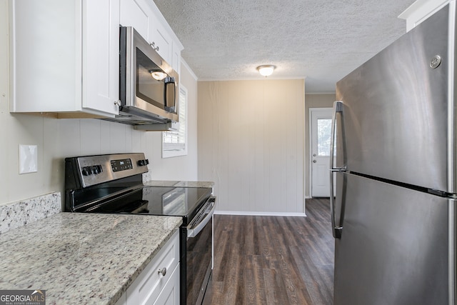 kitchen featuring appliances with stainless steel finishes, white cabinetry, a textured ceiling, dark wood-type flooring, and light stone counters