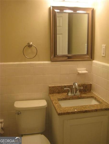 bathroom with tile walls, vanity, and toilet