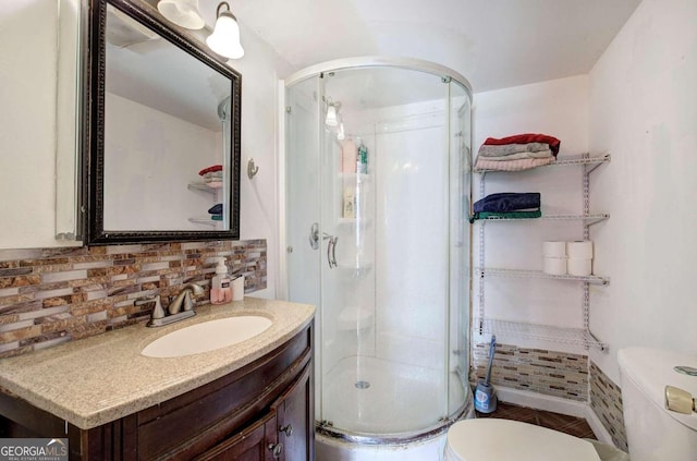 bathroom featuring toilet, a shower with shower door, and vanity