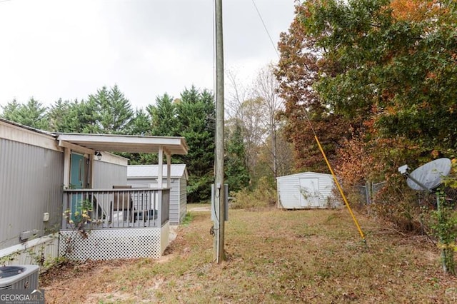 view of yard with a shed, central AC, and a wooden deck