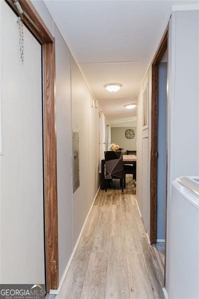 corridor with light wood-type flooring and washer / clothes dryer