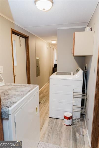 laundry room with electric panel, independent washer and dryer, light wood-type flooring, and cabinets