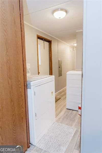 laundry area featuring crown molding, washing machine and dryer, and light hardwood / wood-style flooring