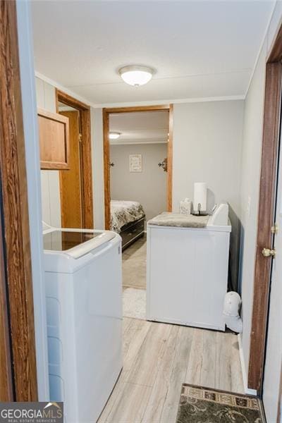 clothes washing area with independent washer and dryer and light wood-type flooring