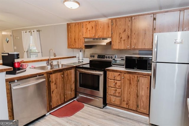 kitchen featuring stainless steel appliances, sink, light wood-type flooring, and backsplash