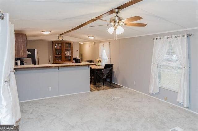 kitchen with kitchen peninsula, stainless steel fridge, light colored carpet, and lofted ceiling