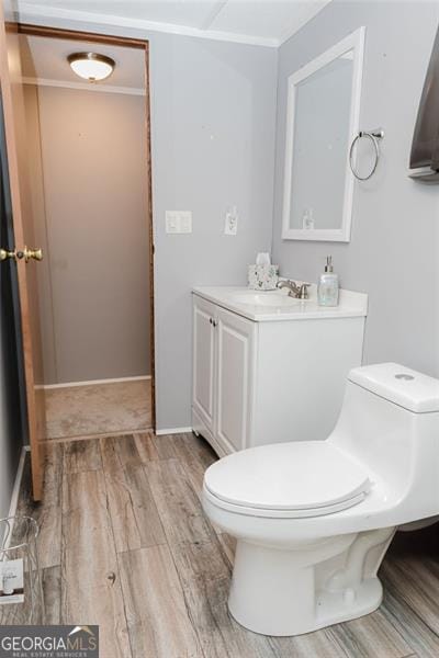 bathroom featuring toilet, crown molding, hardwood / wood-style floors, and vanity