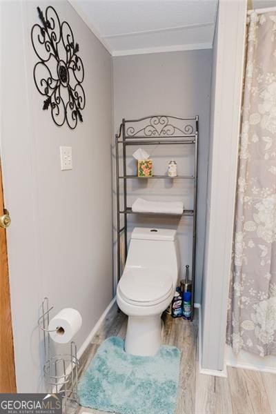 bathroom with toilet, ornamental molding, and wood-type flooring