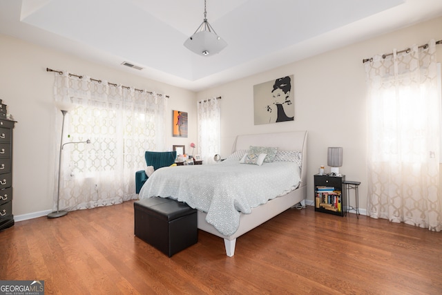 bedroom with hardwood / wood-style floors and a raised ceiling