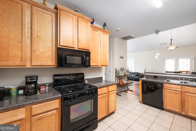 kitchen with dark stone counters, light tile patterned flooring, black appliances, pendant lighting, and sink