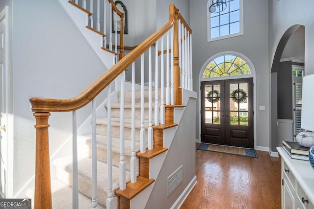 entrance foyer featuring hardwood / wood-style floors, french doors, and a towering ceiling