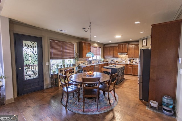 dining space featuring wood-type flooring and crown molding