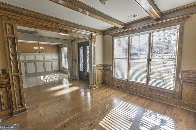 interior space featuring visible vents, a decorative wall, a chandelier, beamed ceiling, and hardwood / wood-style floors