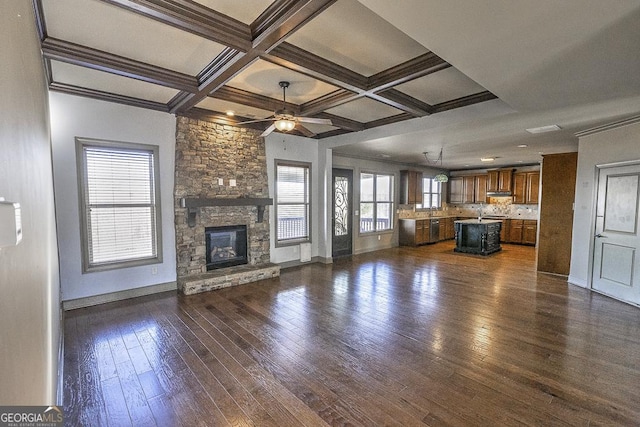 unfurnished living room featuring dark wood-type flooring, coffered ceiling, a fireplace, and baseboards