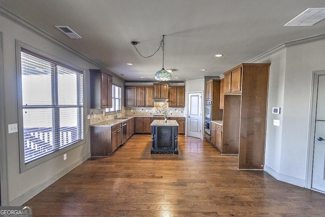 kitchen with visible vents, a kitchen island, ornamental molding, dark wood-type flooring, and light countertops